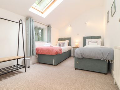 A bedroom with two single beds each with folded towels and striped pillows at Penpoll in Falmouth