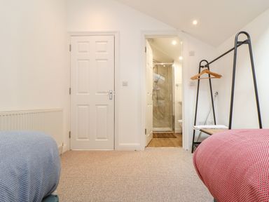 A bedroom with two single beds a black clothes rack and an en suite bathroom at Penpoll in Falmouth