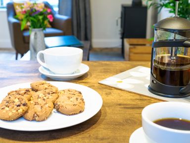 A kitchen table with a plate of cookies cups of coffee and a French press at Porthallow in Mawnan Smith Near Falmouth