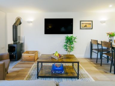 A living room with a wooden coffee table and a wall-mounted TV at Porthallow in Mawnan Smith Near Falmouth