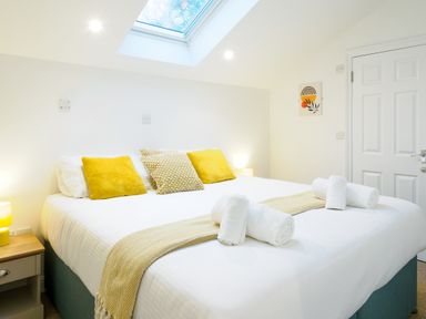 A bedroom with a bed with yellow pillows and rolled towels under a skylight at Porthallow in Mawnan Smith Near Falmouth