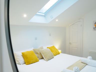 A bedroom with a bed with yellow and patterned cushions under a skylight at Porthallow in Mawnan Smith Near Falmouth