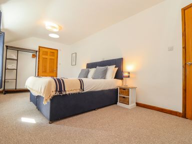 A bedroom with a bed a bedside table with a lamp and a clothes rack at St Keverne in Mawnan Smith Near Falmouth