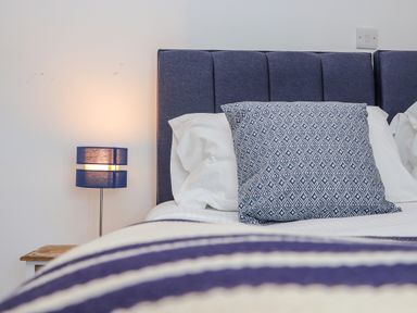 A bed with a blue patterned pillow and blue headboard next to a blue lamp on a wooden side table at St Keverne in Mawnan Smith Near Falmouth
