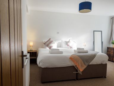 A bedroom with a double bed bedside tables lamps and a standing mirror at Manacles in Mawnan Smith Near Falmouth
