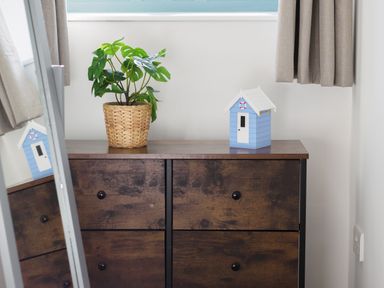 A wooden cabinet with four drawers a potted plant and a blue miniature house with a white roof at Manacles in Mawnan Smith Near Falmouth