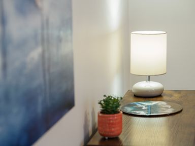 A wooden table with a small potted plant a lamp and a round decorative object at Manacles in Mawnan Smith Near Falmouth