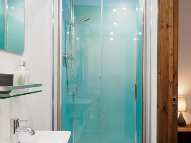 A bathroom with a glass shower enclosure a sink with a faucet and a glass shelf holding soap at Manacles in Mawnan Smith Near Falmouth
