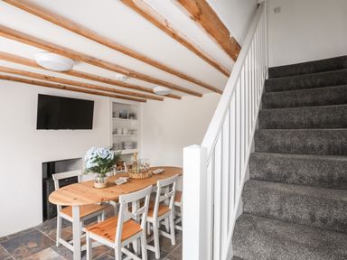 A dining area with a wooden table and chairs next to a staircase with carpet at Isfryn Llanengan near Abersoch