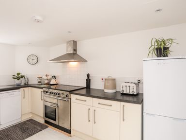 A kitchen with a stove dishwasher toaster refrigerator and countertop items at Isfryn in Llanengan near Abersoch