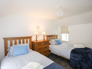 A bedroom with two single beds a wooden chest of drawers and two lamps at Isfryn Llanengan near Abersoch