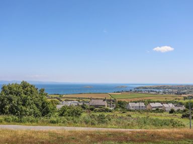 A coastal landscape with houses fields and the sea in the background at Isfryn in Llanengan near Abersoch