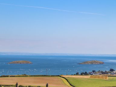 A coastal landscape with two small islands and boats on water near fields and houses at Isfryn in Llanengan near Abersoch