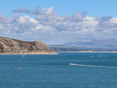 A coastal view with a rocky cliff and boats on the water at Isfryn in Llanengan near Abersoch