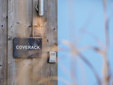 A wooden wall with a sign reading Coverack a light fixture and a combination lockbox at Coverack Mawnan Smith Near Falmouth