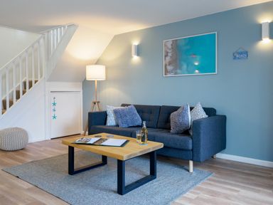 A living room with a dark grey sofa and coffee table under a staircase at Coverack in Mawnan Smith Near Falmouth