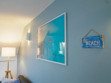 A corner of a room with a floor lamp a framed picture and a wall hanging that says to the beach at Coverack in Mawnan Smith Near Falmouth