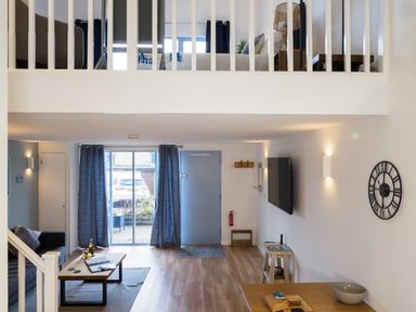 A living area with a couch coffee table and wall mounted tv with stairs leading to an upper bedroom at Coverack in Mawnan Smith Near Falmouth