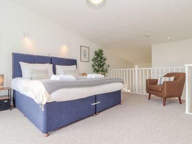 A bedroom with a blue double bed a brown armchair and a potted plant at Helford in Mawnan Smith Near Falmouth
