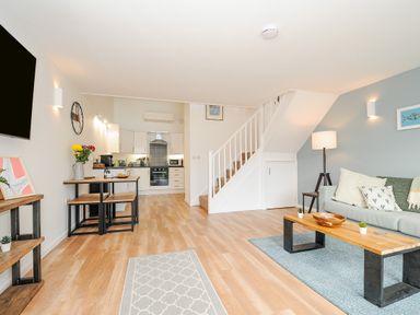 An open living space with a sofa table stairs and kitchen area at Mousehole in Mawnan Smith Near Falmouth