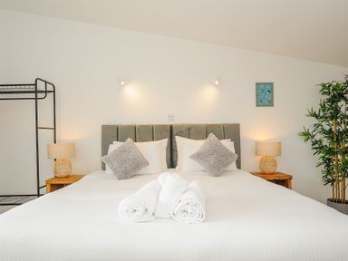 A bedroom with a bed with folded towels and pillows with bedside tables and lamps at Mousehole in Mawnan Smith Near Falmouth