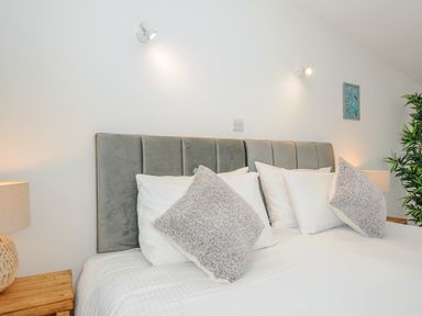 A bed with gray headboard white pillows and gray cushions in a bedroom at Mousehole in Mawnan Smith Near Falmouth