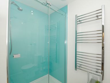 A bathroom with a glass shower enclosure and a wall-mounted chrome towel radiator at Mousehole in Mawnan Smith Near Falmouth