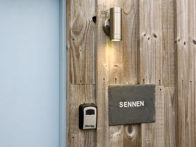 A wooden wall with a light fixture a lockbox and a sign that says SENNEN at Sennen in Mawnan Smith Near Falmouth