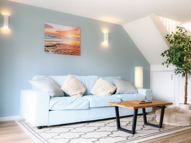 A blue sofa with cushions a wooden coffee table and a potted plant in a living room at Sennen in Mawnan Smith Near Falmouth