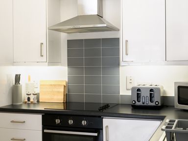 A kitchen counter with a stove knife block cutting boards toaster and microwave at Sennen Mawnan Smith Near Falmouth