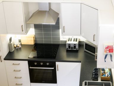 A kitchen counter with a stovetop oven toaster microwave knife block and two mugs at Sennen in Mawnan Smith Near Falmouth