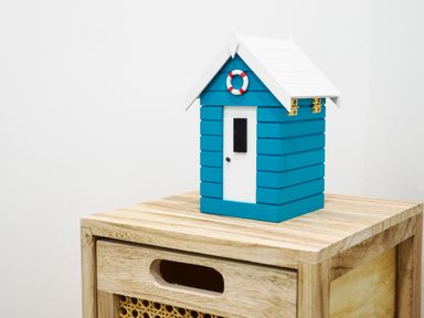 A small blue and white model house on a wooden drawer unit