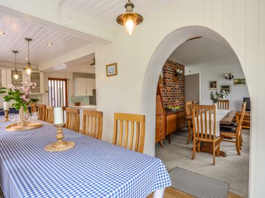 A dining room with a large table covered with a blue and white checkered tablecloth and wooden chairs at Ynys Castell in Menai Bridge
