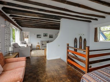 A living area with multiple sofas wooden ceiling beams and railing at Ynys Castell Menai Bridge