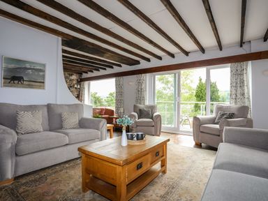 A living room with grey sofas a wooden coffee table and glass doors opening to a balcony at Ynys Castell in Menai Bridge