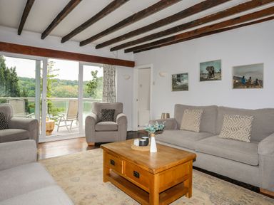 A living room with three gray sofas wooden coffee table and large glass sliding door at Ynys Castell in Menai Bridge