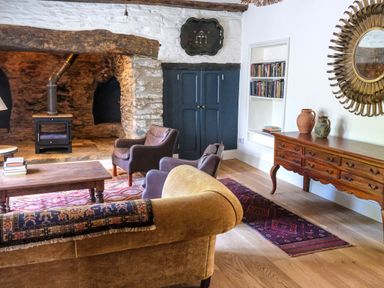 A living room with a wood stove fireplace leather chairs a wooden coffee table and a wooden sideboard at Henllys in Newport Pembrokeshire