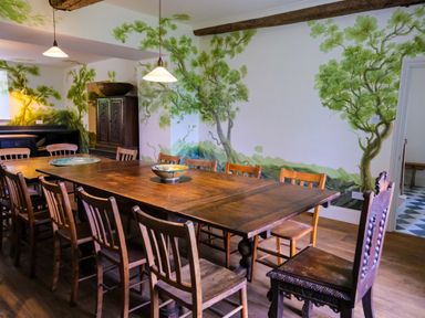 A dining room with wooden tables and chairs and tree murals on the walls at Henllys in Newport Pembrokeshire