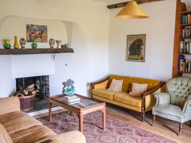 A living room with a fireplace sofa armchair coffee table and bookshelf at Henllys in Newport Pembrokeshire