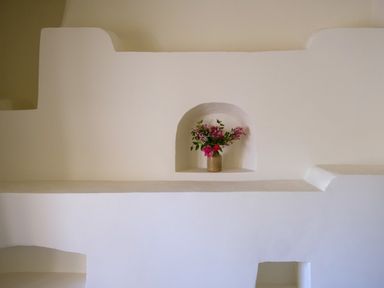 A beige vase with pink flowers in a wall niche with a white plaster wall at Henllys Newport Pembrokeshire