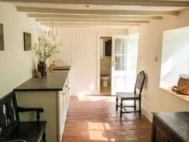 A room with wooden chairs a countertop with a vase and a glimpse into a bathroom at Henllys in Newport Pembrokeshire