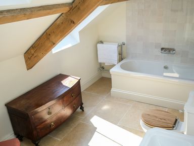 A bathroom with a bathtub towel rack wooden dresser and wooden toilet seat at Henllys in Newport Pembrokeshire