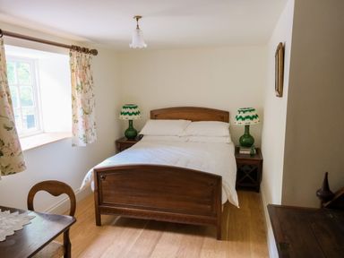 A bedroom with a wooden bed and two bedside tables with green lamps at Henllys in Newport Pembrokeshire