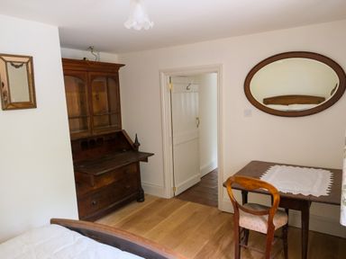 A bedroom with wooden desk and chair mirror and a white door at Henllys in Newport Pembrokeshire