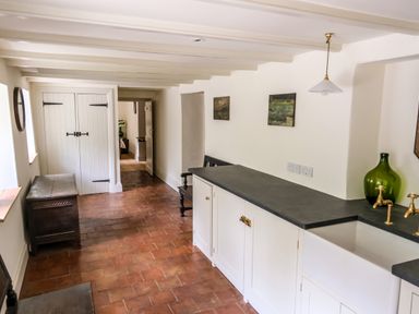 A hallway with white cabinets and a sink on the right and wooden chest and bench on the left at Henllys in Newport Pembrokeshire