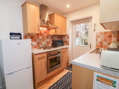 A kitchen with a refrigerator stove oven microwave toaster and a door with a window at Lilyvale in Davidstow near Camelford