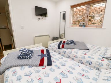A bedroom with two single beds a wall mounted tv a window with blinds and a mirror at Lilyvale Davidstow near Camelford