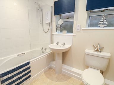 A bathroom with a bathtub shower sink and toilet with nautical decorations at Lilyvale in Davidstow near Camelford