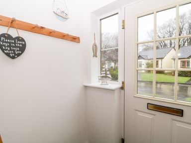 An entrance hallway with a coat rack a heart shaped sign and a model sailboat on the windowsill at Lilyvale in Davidstow near Camelford