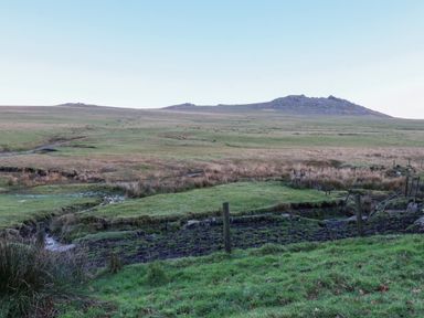 A grassy field with a wire fence and a hill in the background at Lilyvale Davidstow near Camelford